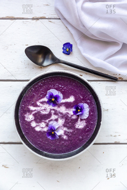 Bowl of creamed red cabbage soup garnished with edible flowers
