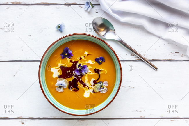 Bowl of creamed pumpkin soup garnished with edible flowers