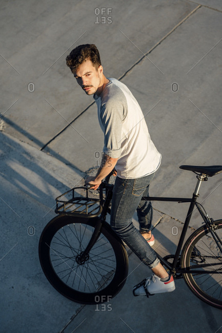 Young man with commuter fixie bike on concrete slabs stock photo - OFFSET