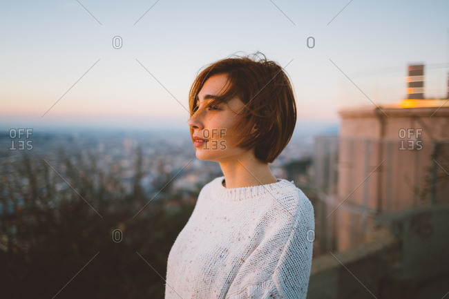 Woman looking at the sun rising in Barcelona city lookout