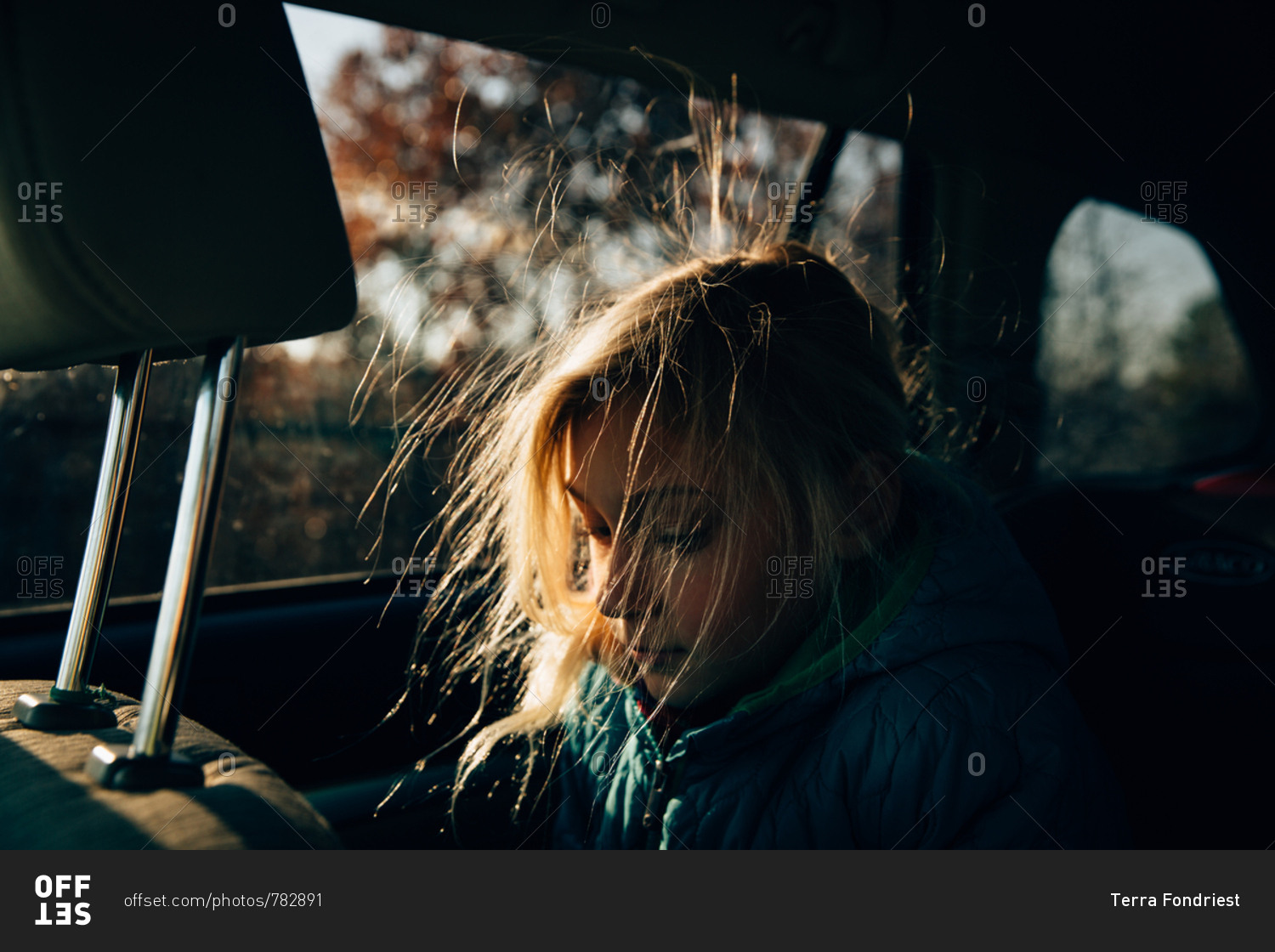 A girl in car with static hair lit up by the sun