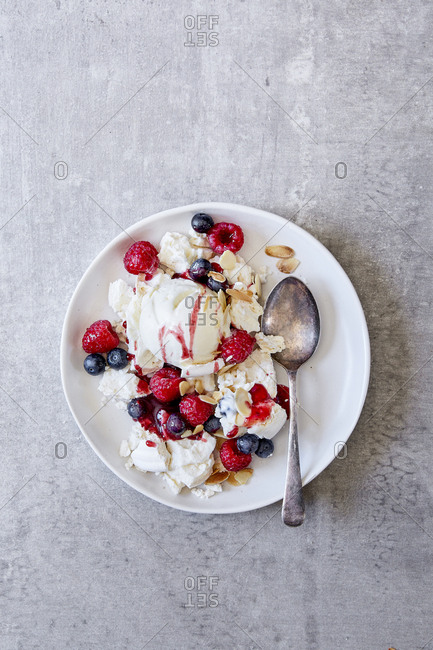 Raspberry and blueberry eton mess with flaked almonds and a spoon