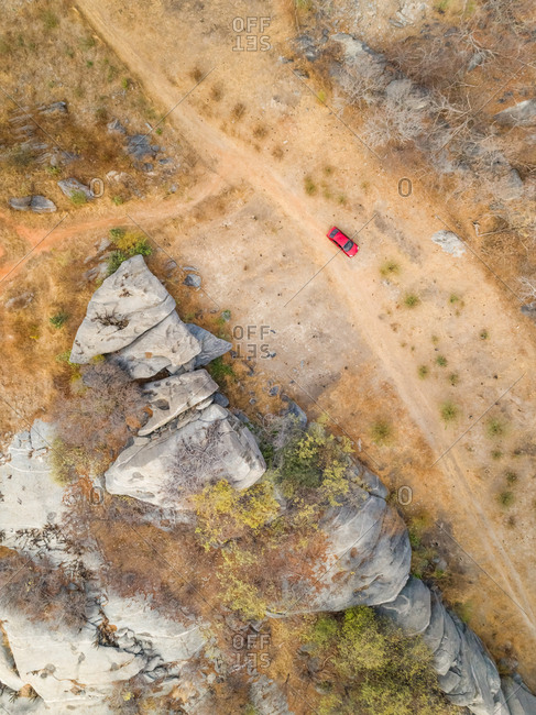 Aerial view of red car parking next to rock formation on arid area, Ceara, Brazil.