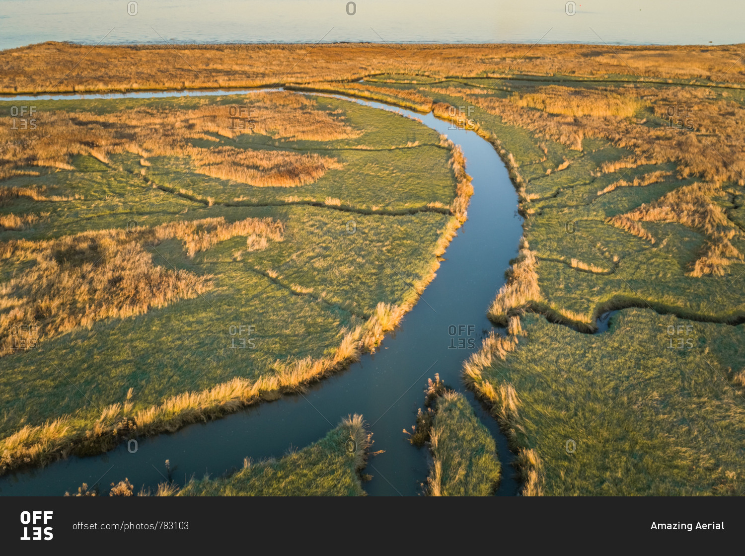 Aerial view of small river crossing wetland during sunset, Netherlands.