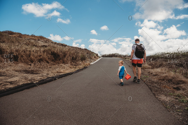 Father and toddler son hiking on path