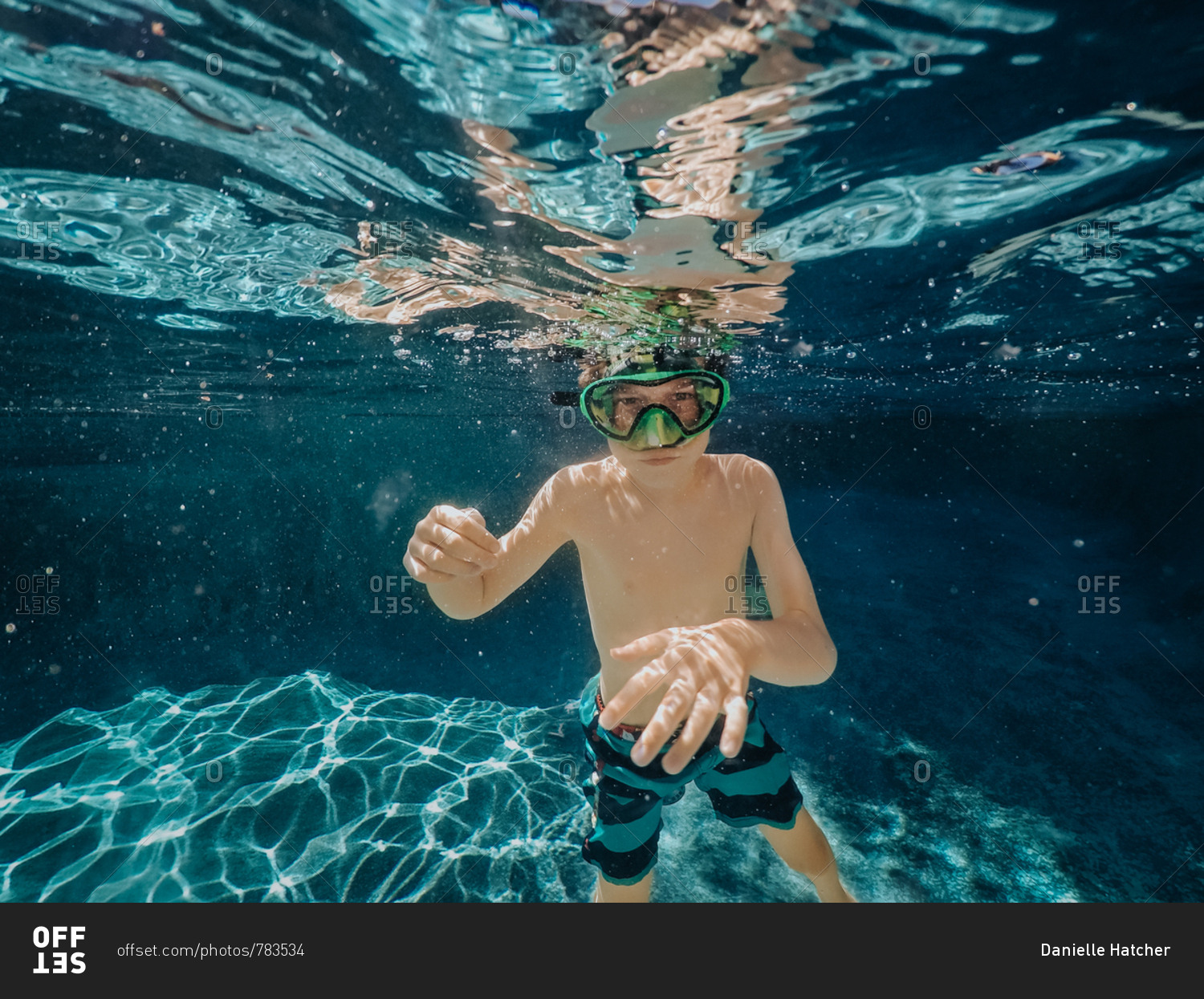 Boy wearing green goggles underwater in pool stock photo OFFSET