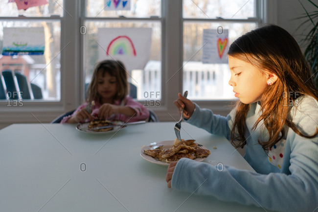 Two girls sitting at a table eating pancakes for breakfast