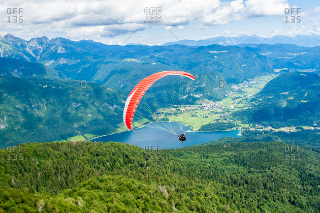 Paraglider sails over Lake Bohinj and its mountains, Slovenia, Europe