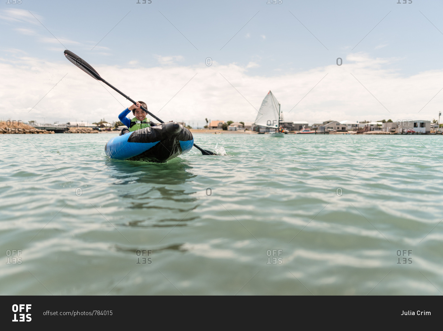 Boy paddling in a blue inflatable kayak near Hawke's Bay, New Zealand