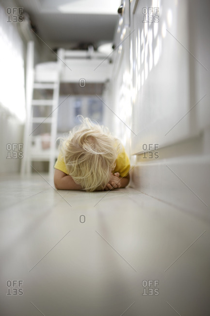 Young boy lying on the floor and hiding his face.