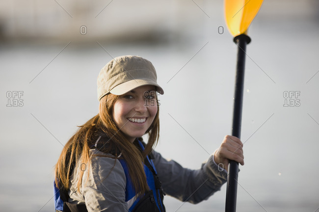 Portrait of a smiling mid-adult woman holding an oar.