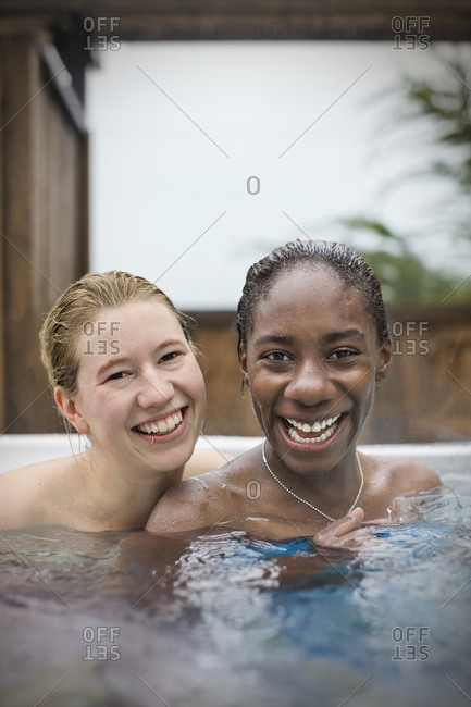 Portrait of smiling young lesbian couple sitting in a hot tub.