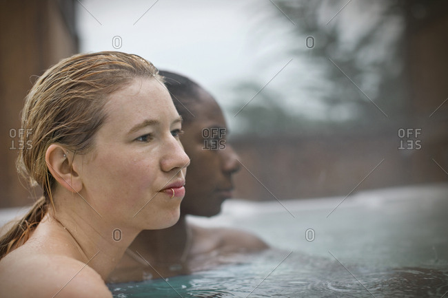 Young woman with a lip ring sitting in a hot tub with wet hair.