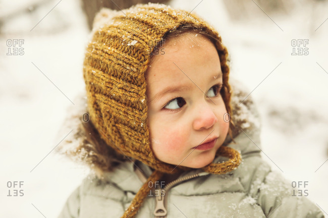 Cute toddler in a knitted hat in the snow