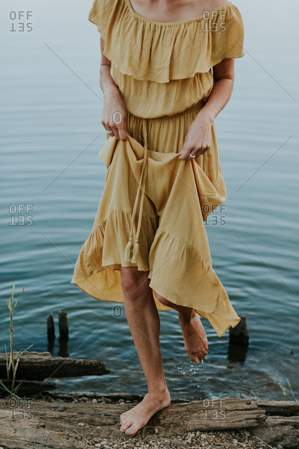 Woman in a yellow dress stepping out of a lake