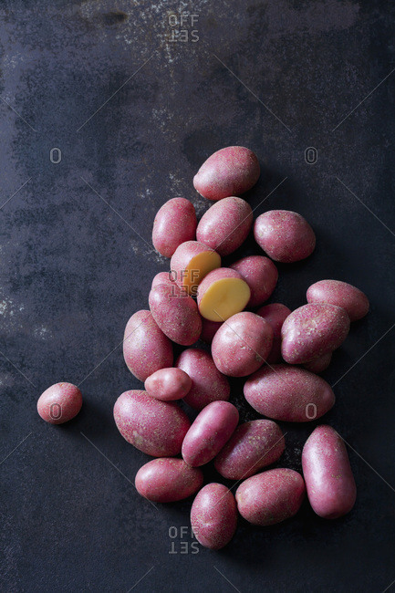 Sliced and whole red baby potatoes on rusty metal