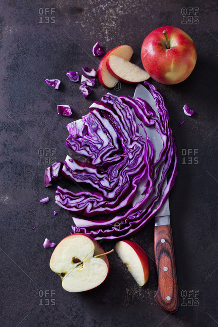 Sliced and red cabbage and apples on rusty ground