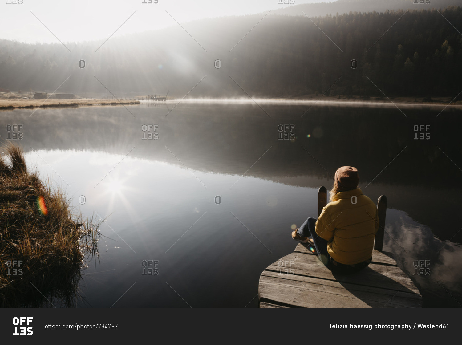 Switzerland- Engadine- Lake Staz- woman sitting on a jetty at lakeside in morning sun