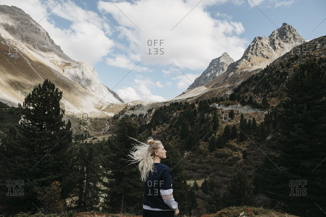 Switzerland- Grisons- Albula Pass- young woman with windswept hair standing in mountainscape