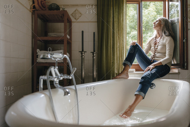 Woman taking a bubble bath in bathroom at home stock photo - OFFSET
