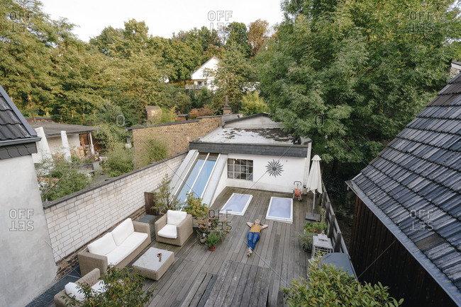Woman with headphones lying on terrace listening music