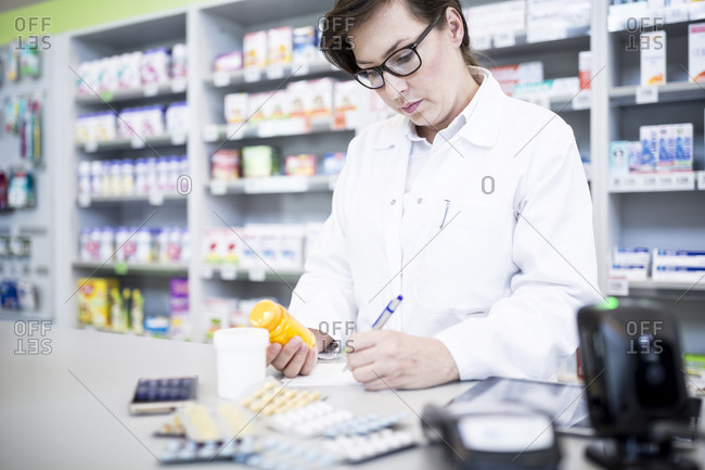 Pharmacist with medicine at counter in pharmacy