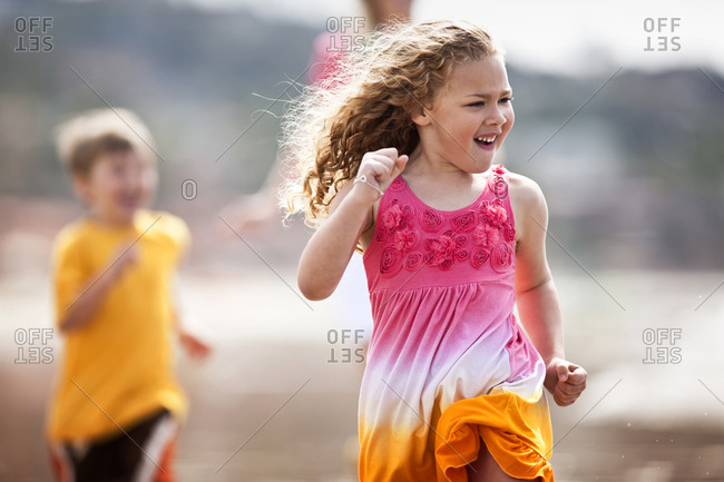 Brother and sister running along the beach.