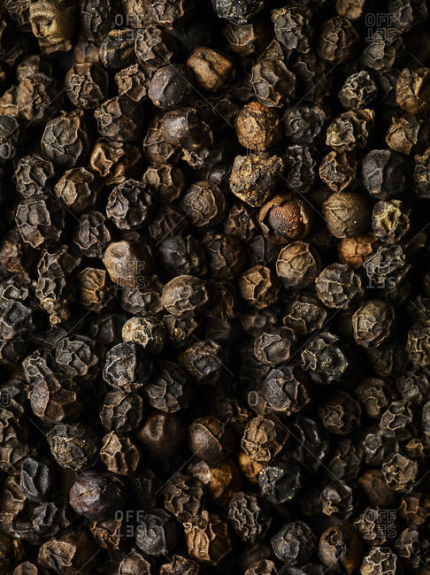 Macro shot of whole black peppercorns fiilling the frame, shot from above.