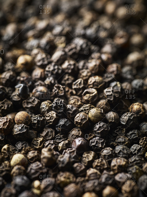 Macro shot of whole black peppercorns fiilling the frame, shot from a low angle
