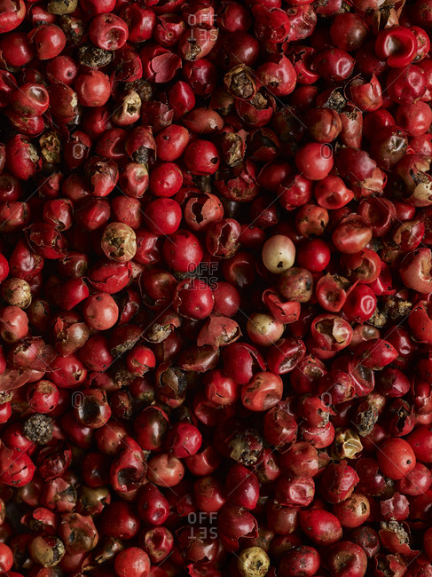 A macro shot of whole and broken pink peppercorns shot from above filling the frame.