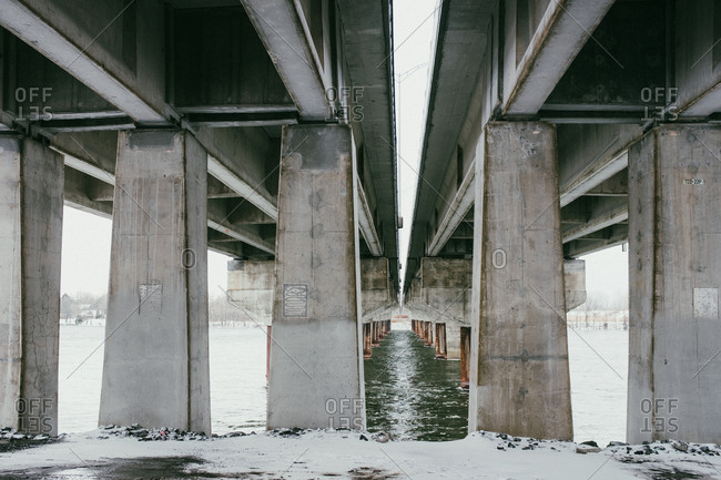 Snowy ground and cold river under freeway
