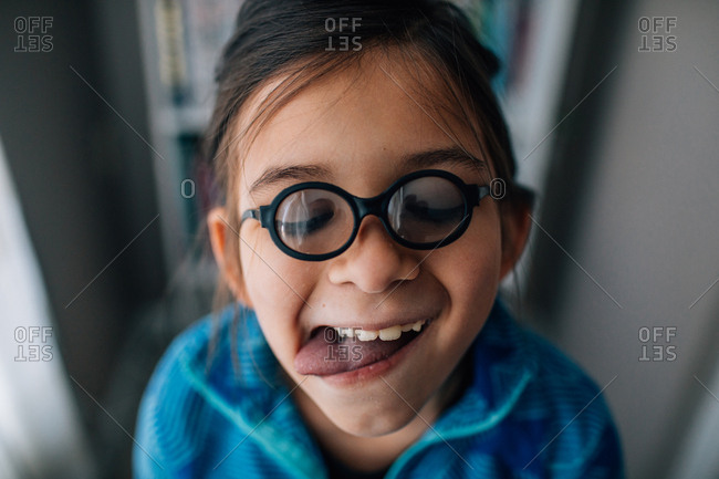 Portrait of a goofy young girl wearing tiny glasses and sticking tongue out