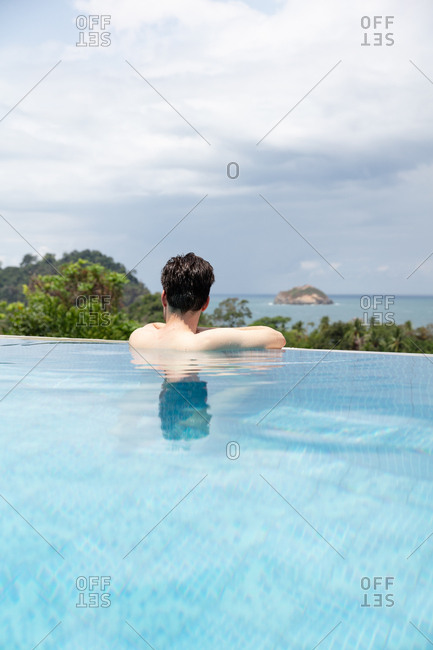 Man swimming in infinity pool on summer holiday