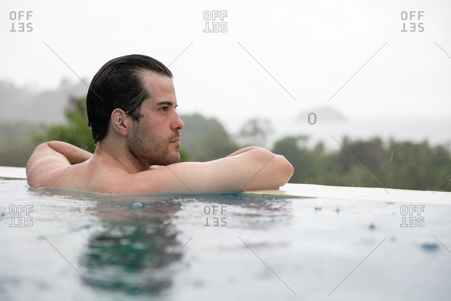 Man in infinity pool whilst raining
