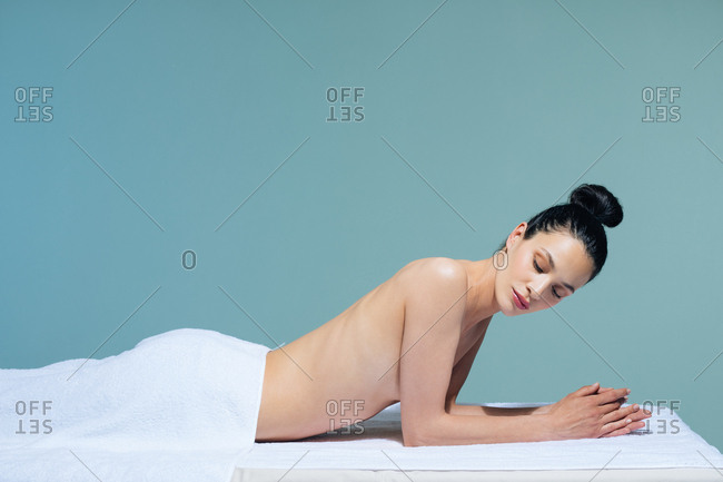 Beautiful Caucasian woman relaxing on massage table at wellness salon.