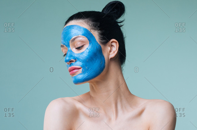 Portrait of beautiful Caucasian woman brunette with blue clay cosmetic face mask.