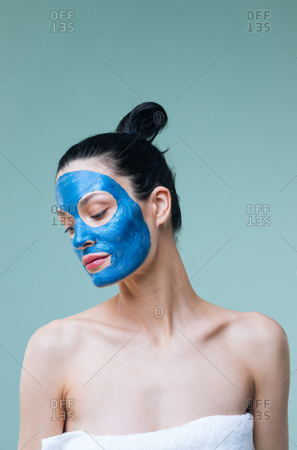 Portrait of pretty Caucasian woman brunette with blue clay cosmetic face mask.
