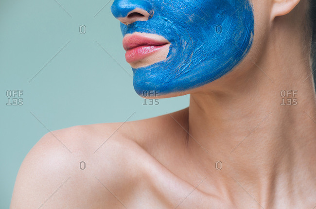 Unrecognisable woman posing with blue clay cosmetic face mask.