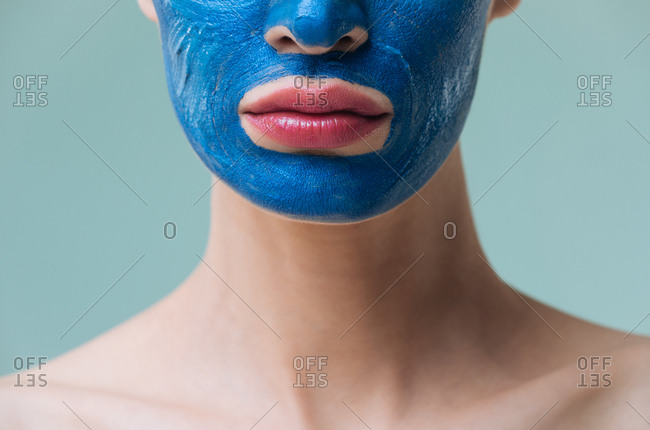 Unrecognisable woman posing with blue clay cosmetic face mask.