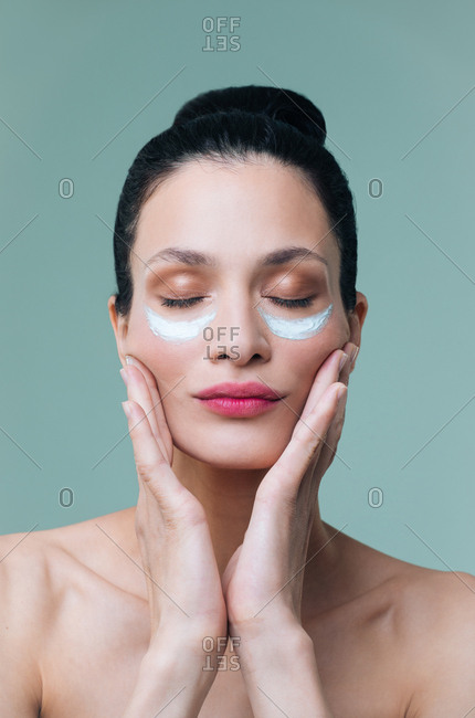 Studio portrait of beautiful Caucasian woman model posing with cosmetic mask under her eyes.