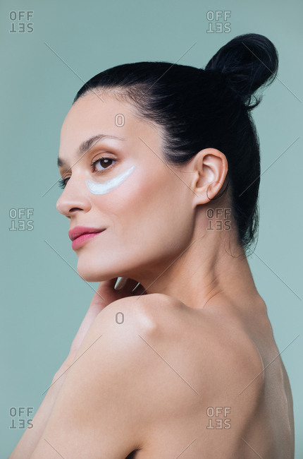 Studio portrait of beautiful Caucasian woman model posing with cosmetic mask under her eyes.