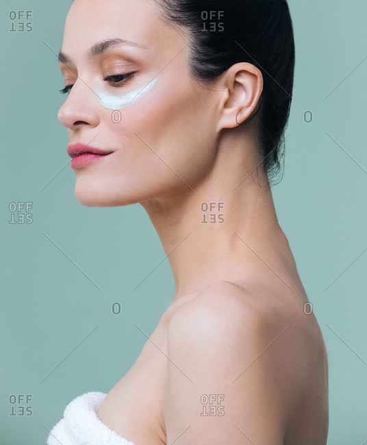 Studio portrait of beautiful Caucasian woman model posing with cosmetic mask under her eyes.