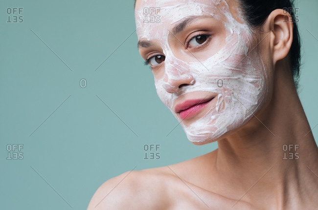 Beautiful Caucasian woman model posing with cosmetic scrub cream on her face.