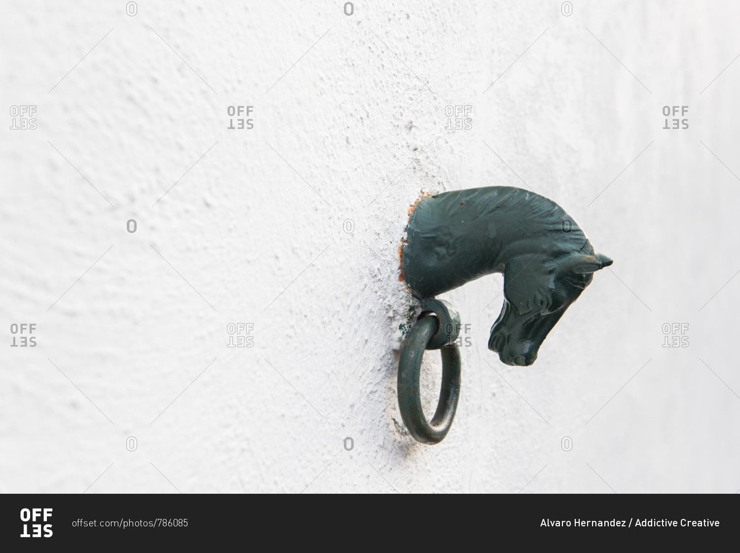 Side view of black decorative figure of horse with ring on white stone wall of building in Pyrenees