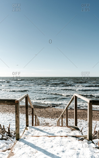 Wooden steps in snow near sea coast and blue sky in Klaipeda, Lithuania