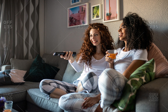 Young Cheerful Women Friends Seating On The Sofa Watching Tv Stock