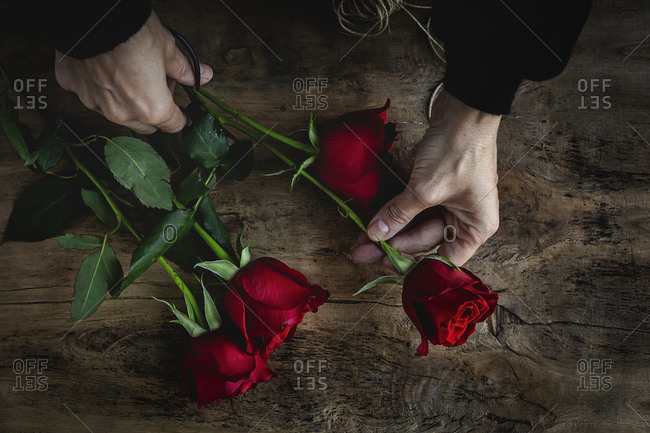 Unrecognizable woman making a bouquet of red roses for Valentine\'s Day. Love. Flat lay