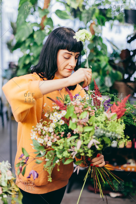 Florist making a flower bouquet from colorful flowers. Flower shop, business owner. Work and occupation.