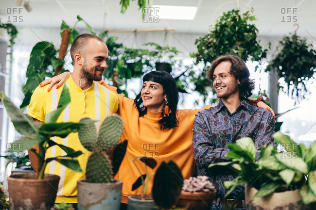 Woman and two men in the flower shop, surrounded by plants. Team, work, small business.