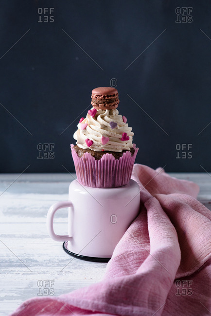 A Valentine\'s day themed cupcake with cream and hearts decoration